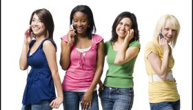 Four women talking on cell phones smiling