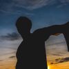 Silhouette Man Gesturing Thumbs Down Against Sky During Sunset