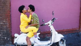 Young couple kissing on the back of a scooter