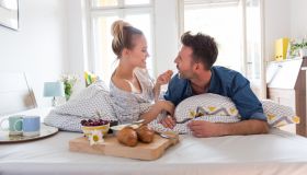 Happy couple eating breakfast in the bed at home