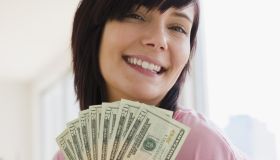 Young woman holding money, smiling