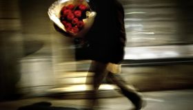 A man carries a bouquet of red roses dur