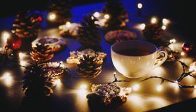 Close-Up Of Coffee Cup And Gingerbread Cookies Amidst Illuminated Christmas Lights