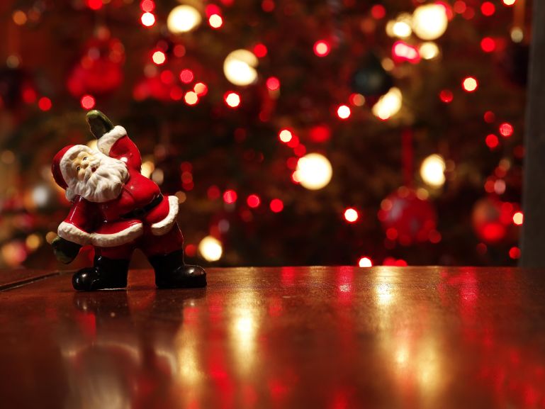 Santa figurine on table in front of Christmas tree