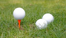 Golf club and golf balls on green grass