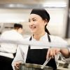 Smiling female chef stirring pot in kitchen at restaurant