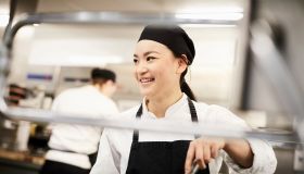 Smiling female chef stirring pot in kitchen at restaurant
